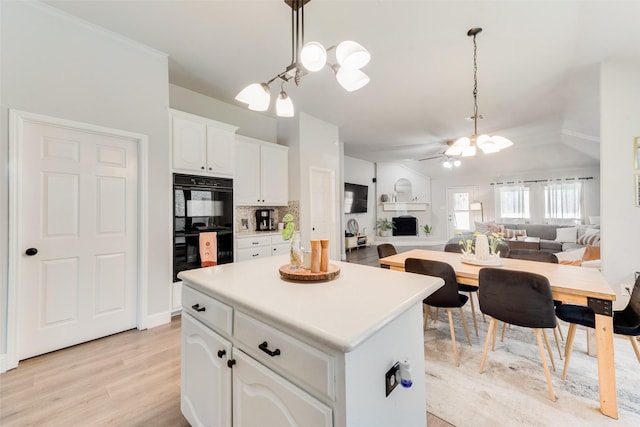 kitchen featuring ceiling fan, backsplash, pendant lighting, vaulted ceiling, and white cabinets