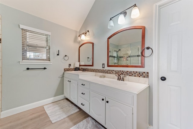 bathroom with tasteful backsplash, a shower, wood-type flooring, vaulted ceiling, and vanity