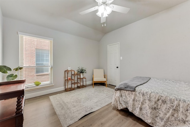 bedroom with ceiling fan, light wood-type flooring, and vaulted ceiling