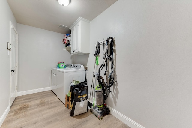 washroom featuring washer and clothes dryer, light hardwood / wood-style floors, and cabinets