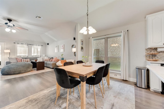 dining area featuring ceiling fan with notable chandelier, light hardwood / wood-style floors, and lofted ceiling