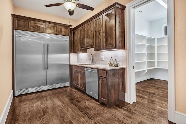 kitchen featuring sink, decorative backsplash, dark brown cabinets, dark hardwood / wood-style flooring, and stainless steel appliances