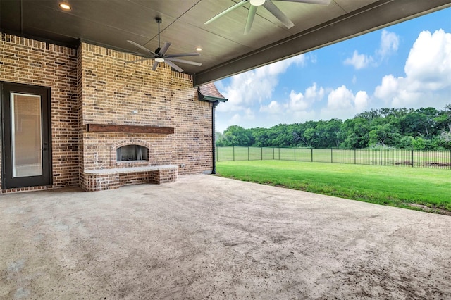 view of patio / terrace with an outdoor brick fireplace, ceiling fan, and a rural view