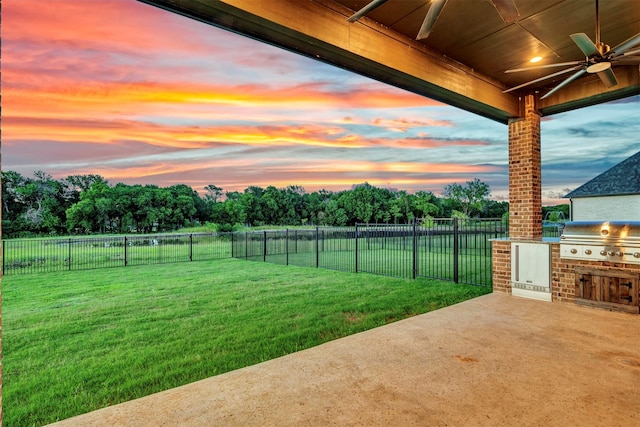 yard at dusk with a patio area, ceiling fan, and exterior kitchen