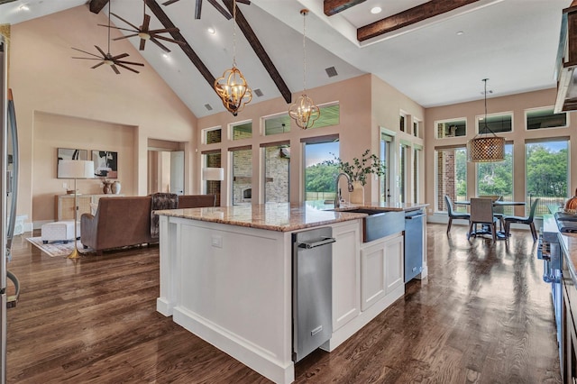 kitchen with white cabinetry, a center island with sink, high vaulted ceiling, and decorative light fixtures