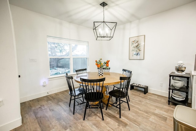 dining room featuring a chandelier, light wood-type flooring, and baseboards