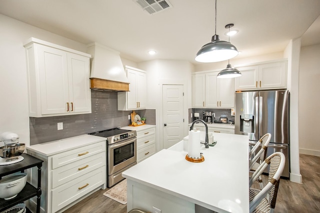 kitchen with a breakfast bar area, custom exhaust hood, light countertops, appliances with stainless steel finishes, and a sink