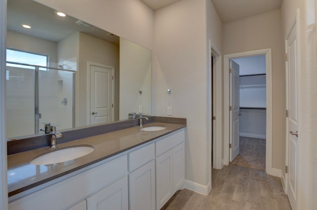 bathroom with hardwood / wood-style floors, vanity, and a shower with door