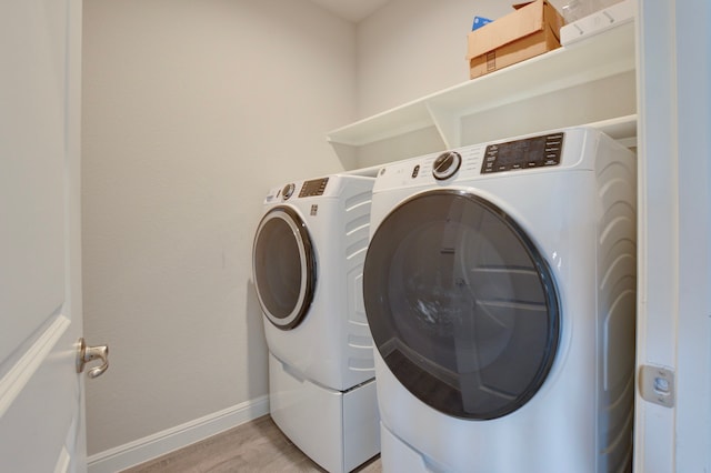 laundry area with light wood-type flooring and washing machine and clothes dryer