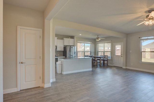 kitchen with white cabinetry, a center island, ceiling fan, and stainless steel refrigerator with ice dispenser