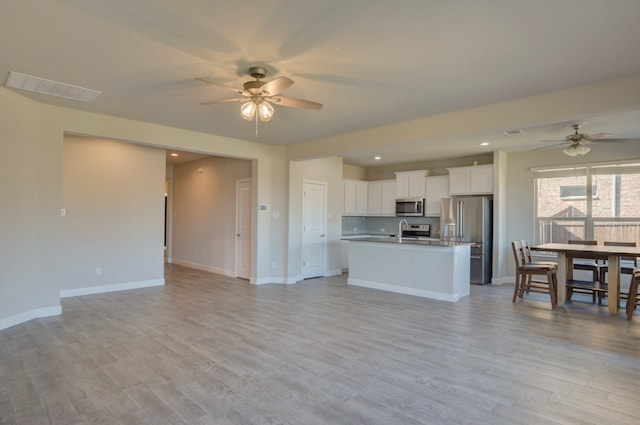 kitchen featuring white cabinetry, ceiling fan, stainless steel appliances, light hardwood / wood-style flooring, and an island with sink