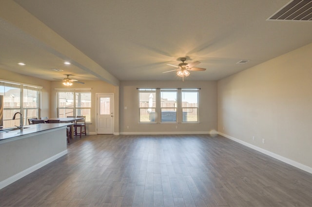 unfurnished living room featuring ceiling fan, dark hardwood / wood-style flooring, and sink