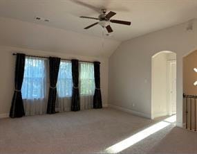 carpeted spare room with ceiling fan, plenty of natural light, and vaulted ceiling