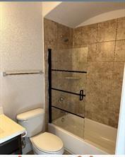 full bathroom with vanity, tiled shower / bath combo, and toilet