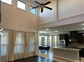 kitchen featuring ceiling fan, a high ceiling, backsplash, a kitchen island, and pool table