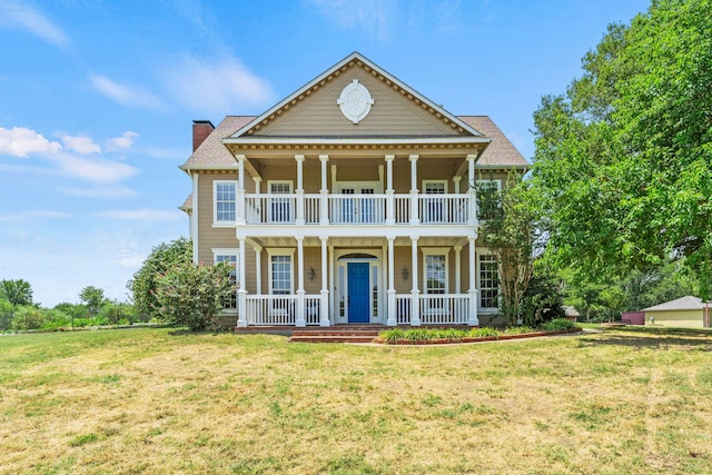 greek revival house with a porch, a chimney, a front yard, and a balcony