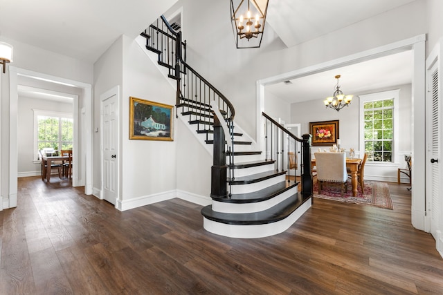 stairs featuring an inviting chandelier, baseboards, and wood finished floors