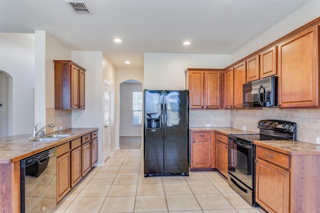 kitchen with tasteful backsplash, sink, light tile patterned floors, and black appliances