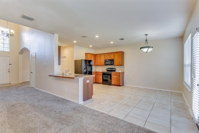 kitchen featuring sink, hanging light fixtures, kitchen peninsula, light colored carpet, and black appliances