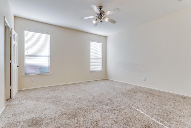 carpeted spare room featuring a wealth of natural light and ceiling fan