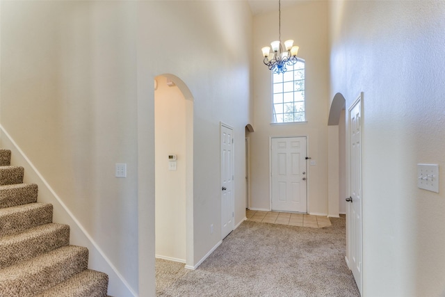 carpeted foyer entrance with a high ceiling and a notable chandelier