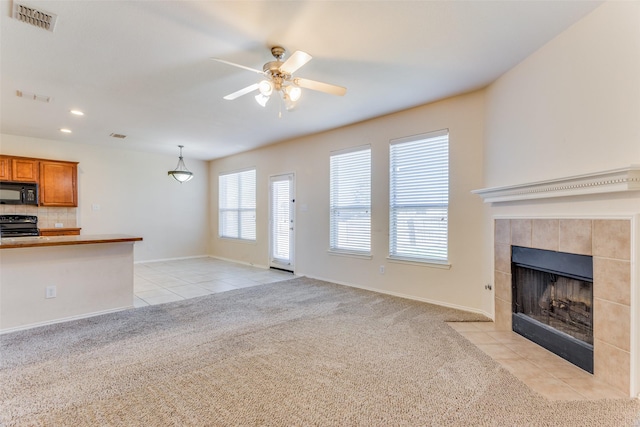 unfurnished living room with ceiling fan, light colored carpet, and a fireplace