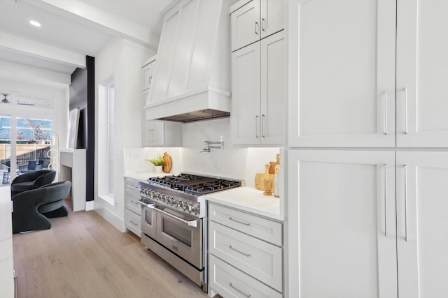 kitchen with white cabinets, custom range hood, light wood-type flooring, and range with two ovens