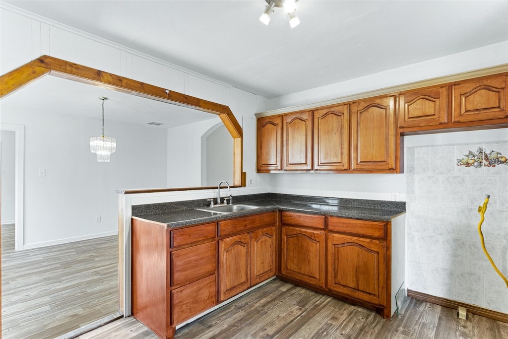 kitchen featuring dark hardwood / wood-style flooring, decorative light fixtures, a notable chandelier, and sink