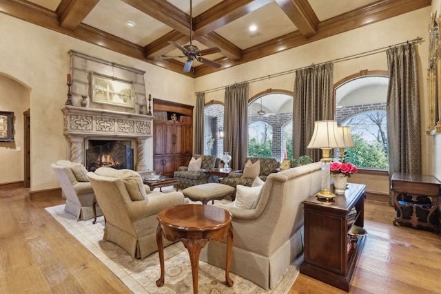 living area with beam ceiling, ceiling fan, light hardwood / wood-style flooring, and coffered ceiling