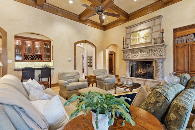 living room featuring ceiling fan, coffered ceiling, beamed ceiling, bar, and ornamental molding