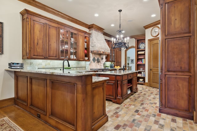 kitchen featuring a center island, hanging light fixtures, premium range hood, kitchen peninsula, and backsplash