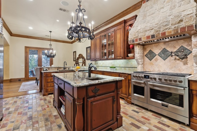 kitchen featuring a center island with sink, sink, double oven range, and premium range hood