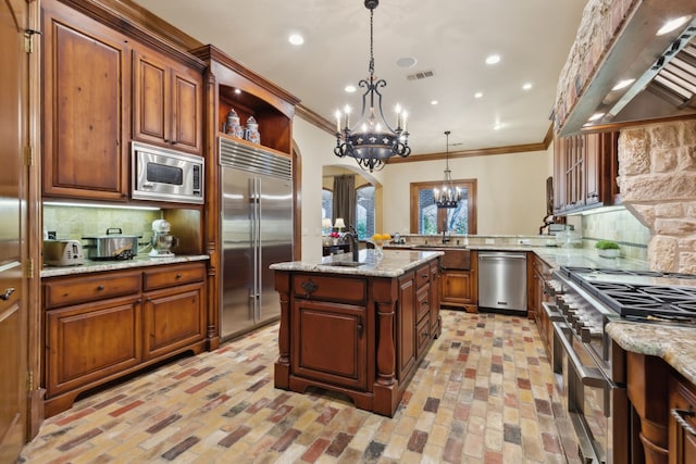 kitchen with range hood, built in appliances, kitchen peninsula, decorative light fixtures, and decorative backsplash