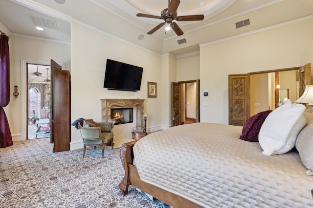 carpeted bedroom with a fireplace, ceiling fan, and ornamental molding