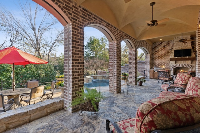 view of patio with an outdoor stone fireplace, area for grilling, ceiling fan, and a grill