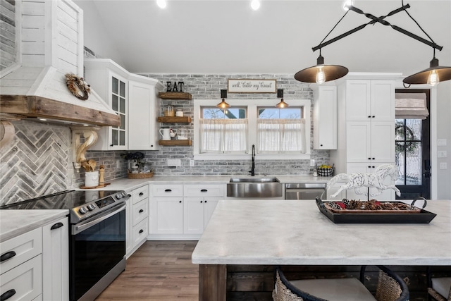 kitchen featuring sink, decorative light fixtures, custom range hood, stainless steel appliances, and white cabinets