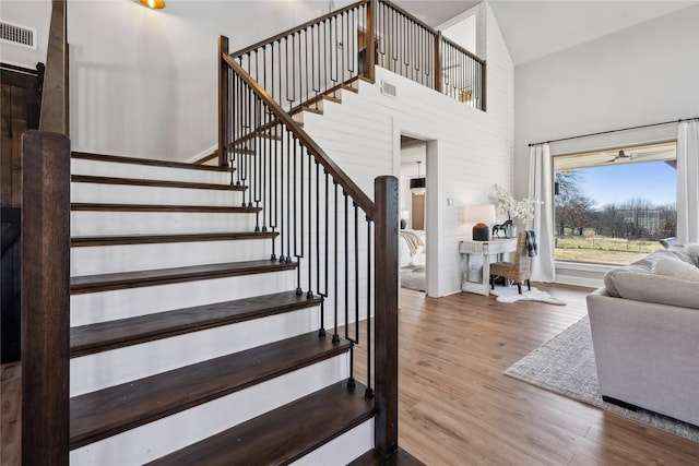 stairway with hardwood / wood-style flooring and a high ceiling