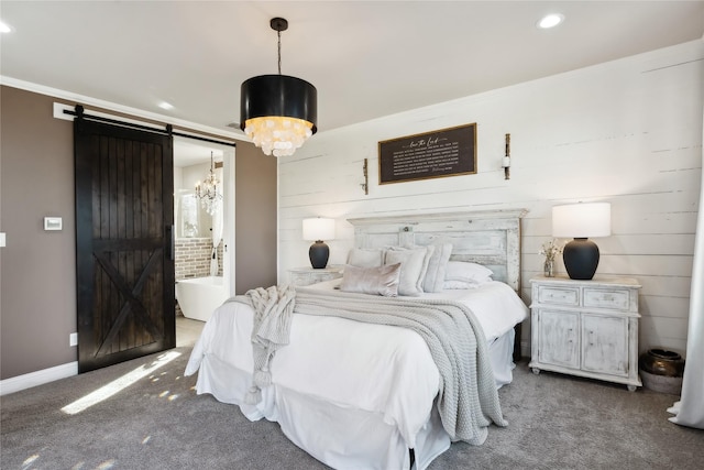 carpeted bedroom with ensuite bath, ornamental molding, a barn door, and a chandelier