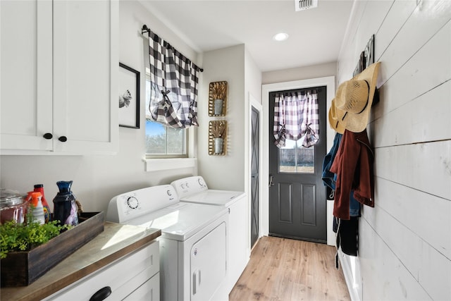 clothes washing area with cabinets, light wood-type flooring, and independent washer and dryer