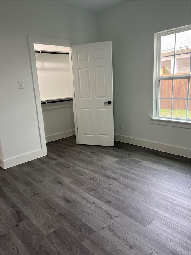 unfurnished bedroom featuring multiple windows, a closet, and dark wood-type flooring