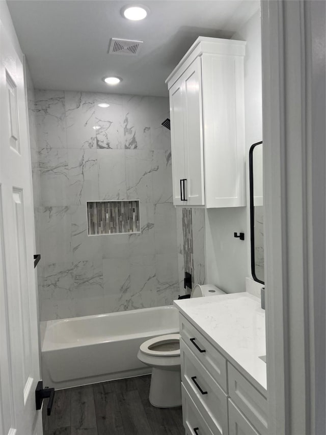 full bathroom with vanity, wood-type flooring, tiled shower / bath combo, and toilet