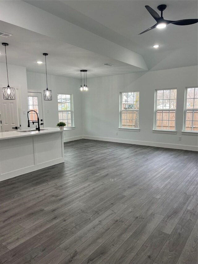 unfurnished living room featuring dark hardwood / wood-style flooring, ceiling fan, and sink