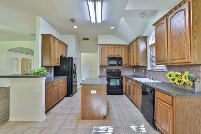 kitchen featuring black appliances, a kitchen island, sink, and tasteful backsplash