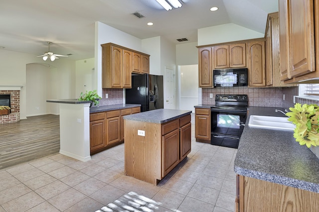 kitchen with a center island, black appliances, sink, ceiling fan, and tasteful backsplash