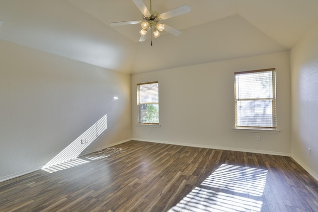 empty room featuring plenty of natural light, dark wood-type flooring, and vaulted ceiling