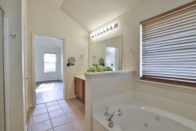 bathroom featuring tile patterned flooring, vanity, a tub, and lofted ceiling