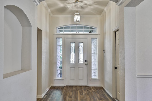 foyer entrance with dark hardwood / wood-style floors, crown molding, and an inviting chandelier