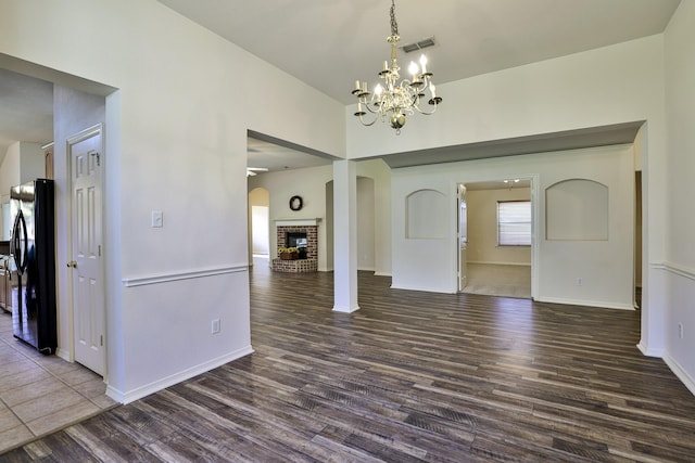 interior space with a chandelier, dark hardwood / wood-style floors, and a brick fireplace