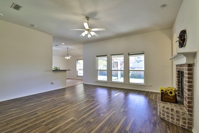 unfurnished living room featuring ceiling fan, dark hardwood / wood-style floors, and a brick fireplace