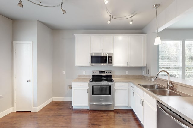 kitchen featuring white cabinets, appliances with stainless steel finishes, decorative light fixtures, and sink